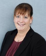 Eine Frau mit schwarzem Blazer und Bordeauxroter Bluse.