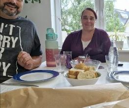 Ein Mann und eine Frau sitzen an einem gedeckten Tisch. Anlass ist die Verabschiedung einer Umschülerin.
