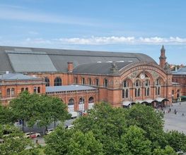 Blick aus dem Fenster auf das Bahnhofsgelände mit einem schönen, großen Gebäude.