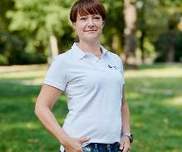 Eine Frau mit kurzen, dunklen Haaren in Jeans und weißem Poloshirt.
