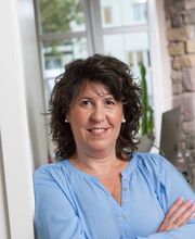 Bild einer brünetten Mitarbeiterin, die freundlich in die Kamera schaut.