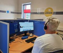 Teilnehmer arbeitet an einem Arbeitsplatz und hat ein Headset auf dem Kopf.
