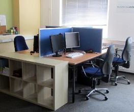 Heller Schulungsraum mit zwei PC-Arbeitsplätzen und einem Regal.