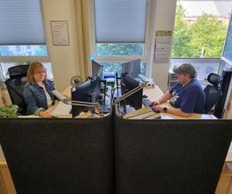 Empfang mit Mitarbeiter:innen, welche am Arbeitsplatz gegenüber sitzen.