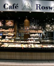 CAFÉ ROSWITHA
„Roswitha von Gandersheim“ durfte es am Ende nicht heißen, aber mit der knapperen Variante, „Café Roswitha“, erhalten wir auf eine liebevolle und persönliche Weise das Andenken an die erste Dichterin Deutschlands aufrecht. Wir laden dich ein, den Stress für die Dauer deines Aufenthaltes im Auto auf dem Parkplatz zurückzulassen und es dir in unserem „Café Roswitha“ im Vorkassenbereich gemütlich zu machen.
Mit dem großen, doppelten Sitzbereich von über 70 Sitzplätzen und einer Außenterrasse mit ca. 30 Sitzplätzen ist für jeden Gast genügend Freiraum garantiert. Bei kaltem Wetter lässt es sich im Innenbereich in der Kaminecke mit einer Tasse frisch gemahlenem Kaffee und einem Stück Kuchen oder Torte in den Sesseln vor dem Kamin wohlfühlen. Das Café ist schon frühmorgens unser „Hotspot“.