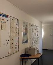 Flur mit 2 Whiteboards auf den Informationszettel hängen. Druckstation mit Papierablage.