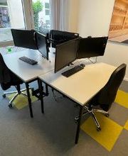 Mehrere Arbeitsplätze in einem Trainingsraum, ausgestattet mit jeweils zwei Monitoren, einem Bürostuhl,  Maus und Tastatur.