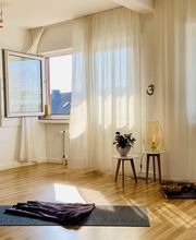 Sonniger Yogaraum mit Matten, Klangschalen und ruhiger Atmosphäre vor Kursbeginn.
