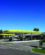 AGROLA Tankstelle in Lohn-Ammannsegg - Bätterkinden; Rechts Totem mit Landi Laden Logo, AGROLA Logo, digitaler Preisanzeige, selfwash; azurblauer Himmel; geschwungenes Dach mit drei Säulen