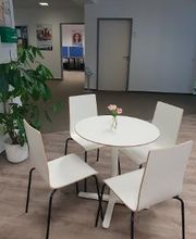 ein runder Tisch mit 4 Stühlen im Aufenthaltsbereich mit einer Dekoblume