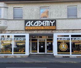 Academy Fahrschule Baumann - Stuttgart Vaihingen - Nahaufnahme des Eingangsbereichs einer Fahrschule in Stuttgart-Vaihingen mit Schaufensterwerbung für Führerschein, Theorieunterricht und praktische Fahrausbildung.