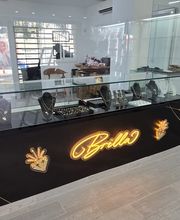 This elegant interior showcases the Brilla Jewelry counter, featuring a sleek black display case filled with fine gold, silver, and diamond jewelry, including necklaces and rings. The neon "Brilla" sign adds a modern touch to this trusted jewelry store, offering luxury watches and professional jewelry repair services. Visit https://joyeriabrilla.com/ for unique pieces and secure pawn services.