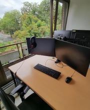 Schreibtisch im Trainingsraum mit zwei Bildschirmen, Tastatur, Maus und Headset.