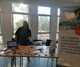 Eine fröhliche Frau steht am Infostand im Jobcenter
