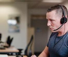 Mann mit Headset sitzt konzentriert am Arbeitsplatz