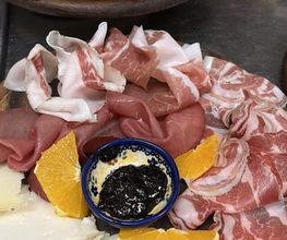 Tagliere di salumi e formaggi con conserve e arancia