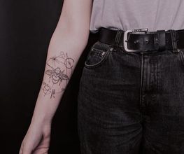 Filigranes Fineline Tattoo mit Biene am Unterarm.