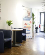 Eingangsbereich mit Tisch, Sesseln und Grünpflanze.