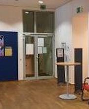 Aufenthaltsbereich mit Stühlen, Tisch und Werbeaufstellern.