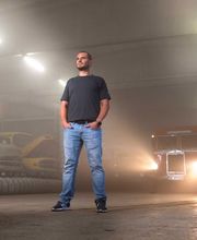 Foto und Filmproduktion Laila Tkotz Porträtaufnahme in Industriehalle mit klassischen Fahrzeugen und Scheinwerfern