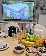 Gedeckter Tisch mit Kaffee, Obst und Plätzchen. Dahinter ein Bildschirm auf dem die digitale Lernumgebung zu sehen ist.