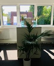 Zwei Schreibtische im Trainingsraum mit jeweils zwei Bildschirmen. Tastatur, Maus und Headset. Eine große Fensterfront mit Blumen.