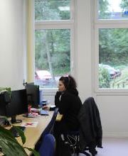 Eine Teilnehmerin sitzt in einem Schulungsraum vor ihrem PC-Bildschirm direkt neben der Fensterfront.
