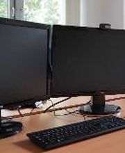 Arbeitsplätze bestehend aus 2 PC-Bildschirmen, Tastatur, Maus und Headset. Im Hintergrund Fenster mit Blick ins Grüne.
