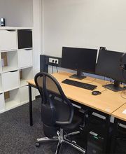 Arbeitsplatz bestehend aus 2 PC-Bildschirmen, Tastatur, Maus und Headset sowie einem schwarzen Bürostuhl. Daneben ein Regal mit mehreren Ablagefächern. 