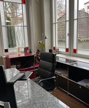 Büro von A. Hampel mit großem Arbeitsplatz direkt an den hellen Fensterflächen.