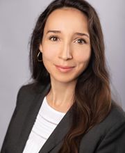 Junge Frau mit langen brünetten Haaren und schwarzem Blazer.