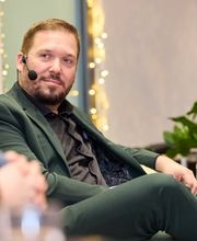 Foto und Filmproduktion Laila Tkotz Mann im Business-Outfit spricht bei Interviewveranstaltung mit Mikrofon