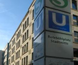 S- iund U-Bahn Hinweisschild Rotebühlplatz Stadtmitte. Dahinter steht ein Bürogebäude.