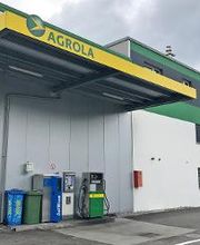 AGROLA Tankstelle in Oberbuchsiten; Eine Tanksäule mit Zahlterminal; daneben auch AdBlue Tanksäule; grüner Mülleimer und PET Behälter; überdacht; rechts weiss-grüne Hausfassade mit AGROLA Logo
