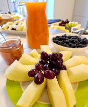 Gesundes Frühstück mit Teilnehmer:innen mit Melonen, Trauben, Tee und Saft.