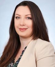 Frau mit langen, dunklen Haaren und beigem Blazer.