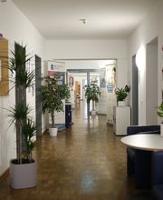 Flur mit Tisch, Sesseln und Grünpflanzen.