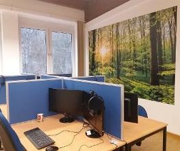 Mehrere abgetrennte PC-Arbeitsplätze mit Monitor, Tastatur, Maus und Headset.