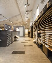 Bodenabteilung mit Tageslichteinfall zur präzisen Farbauswahl. Ausstellung von Massivholzdielen, Parkett, Laminat, Vinyl- und Java Designböden sowie Profilbretter und Paneele