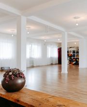 Weitläufige Studioansicht mit hellem Raum, Holzboden und ruhiger Atmosphäre. Das Bild zeigt die offene und freundliche Umgebung für Yoga, Entspannung und Bewegung.