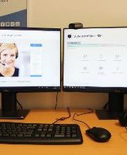 Arbeitsplatz mit zwei Bildschirmen, einer Tastatur, Maus und Headset.