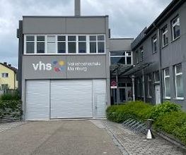 Außenansicht von dem Gebäuder der Volkshochschule Mainburg mit Aufschrift auf der grauen Fassade.