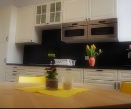 Küche mit Kühlschrank, zwei Mikrowellen und Tisch und Stühlen.