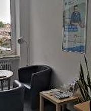 Ein Beratungsbüro mit einem Arbeitsplatz, einem runden Tisch und drei Sesseln