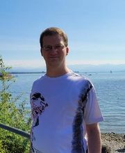 Ein Mann mit weißem Shirt an einem See.