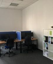 Schulungsraum mit 2 Arbeitsplätzen jeweils mit 2 Bildschirmen, einem Bürostuhl, Tastatur, Maus und Headset. Dahinter ein Bücherregal.