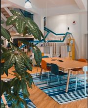 Arbeitsbereich mit Tischen, Stühlen und Grünpflanzen.