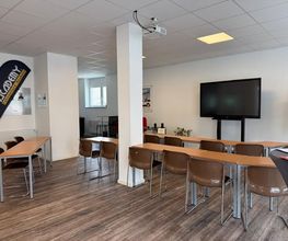 Academy Fahrschule Baumann - Stuttgart Vaihingen - Heller Schulungsraum für Theorieunterricht in Stuttgart-Vaihingen mit Tischen, Stühlen, Bildschirm und moderner Ausstattung zur Prüfungsvorbereitung.