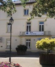 Gelbes Gebäude mit Balkon an dem ein WBS TRAINING Banner hängt. Davor eine Straße und mehrere Pflanzen.