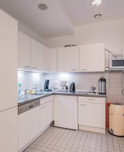 Eine weiße Küche mit Kaffeemaschine, Wasserkocher und Mikrowelle.